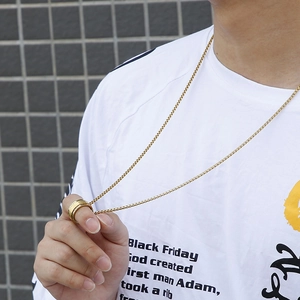 Detail of spinning stainless steel mantra ring and gold pearl chain necklace for men