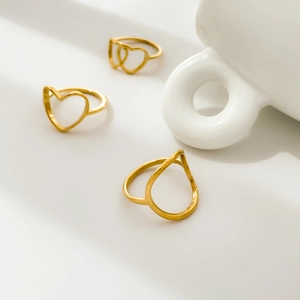 Detail of minimalist gold-tone openwork heart and teardrop geometric design rings