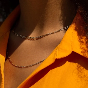 Collier maille Figaro dorée en acier inoxydable porté par un mannequin chic