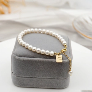Elegant freshwater pearl bracelet with a golden Good Luck charm on a velvet jewelry box