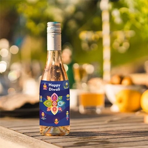 Close-up of Diwali wine bottle label with Rangoli pattern on a sunlit wooden table