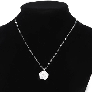 Detail of a white shell flower pendant on a silver stainless steel chain necklace