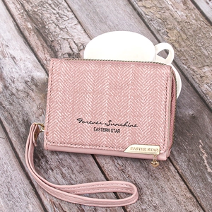 Detailed view of pink fabric wallet with golden heart charm and leather wrist strap
