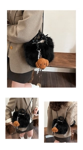 Detail of plush black bucket bag with soft faux fur texture and a cute brown dog charm