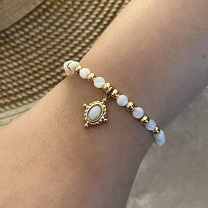 Natural stone beaded bracelet with gold vintage pendant and pearls on woman's wrist