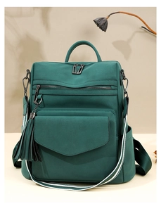 Detail view of green nylon backpack featuring fringe charm and striped shoulder strap
