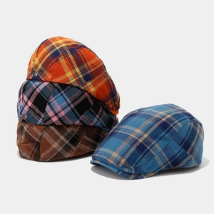 Detail of colorful plaid flat caps showing textured fabric and metal adjustment buckles