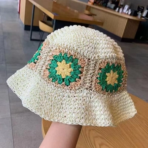 Detail of hand-crocheted cream straw hat with colorful floral patterns in soft light