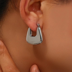 Close-up of a minimalist silver U-shaped hoop earring with a polished mirror finish on ear