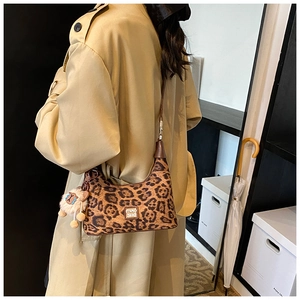 Detail of leopard print hobo bag with sheep plush charm and metal logo on a model