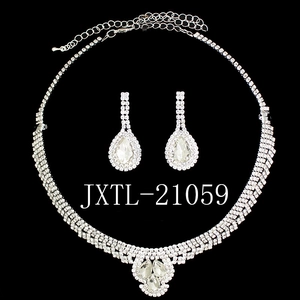 Detail view of silver rhinestone jewelry set with pear-cut crystals on black background