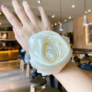 Elegant off-white silk rose scrunchie worn on wrist in a cozy cafe setting