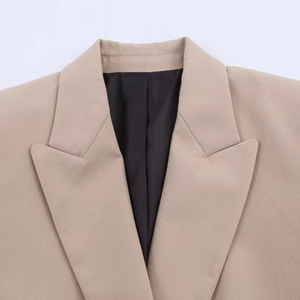 Close-up detail of notched lapel and shoulder tailoring on a beige blazer jacket