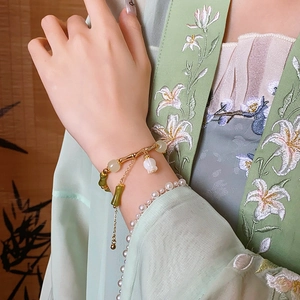 Vue détaillée d'un bracelet en bambou doré avec breloque muguet et perles de jade vert
