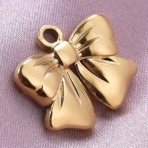 Macro detail of a 304 stainless steel golden bow pendant with a polished reflective finish