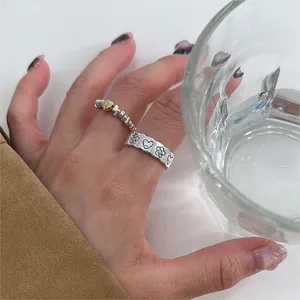 Detail of 925 sterling silver rings with gold heart and floral pattern on hand