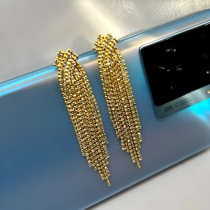 Elegant long gold tassel earrings with sparkling white cubic zirconia on a mobile phone background