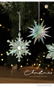 Close-up of iridescent acrylic snowflake and star hanging on a Christmas tree branch