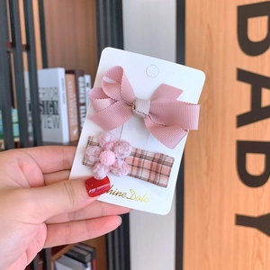 Detailed view of pink bow hair clip and plush flower hairpins on display card