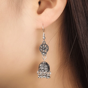 Vue détaillée des boucles d'oreilles Jhumka avec sculptures florales sur l'oreille du mannequin