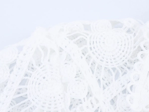 Detailed macro view of white hollow lace fabric with intricate floral embroidery patterns