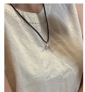 Detail of s925 silver bow pendant with adjustable black cord necklace on a model
