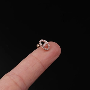 Macro shot of rose gold pig nose stud earring with zircon inlay held on a fingertip