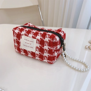 Macro view of red houndstooth tweed cosmetic bag with pearl chain handle and text label
