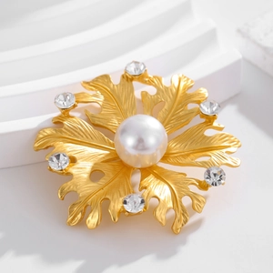 Matte gold flower brooch with central pearl and sparkling crystals in a retro style