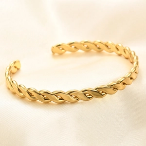 Detail of a 6mm gold twisted cable cuff bracelet resting on silk fabric background