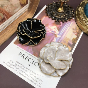 Close-up of black and white enamel flower brooches with gold edges in vintage setting