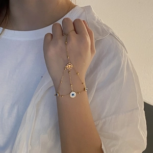 Gold evil eye hand chain bracelet with small beads and blue charms on a female model