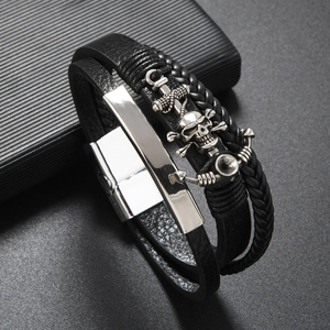 Detail of men's multilayer black leather bracelet with silver skull and anchor charms