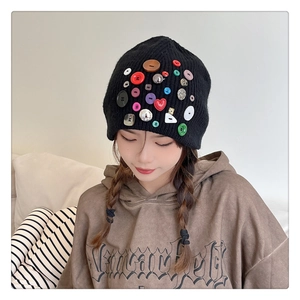Close-up of black knitted beanie with colorful decorative buttons in various shapes