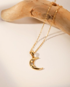 Détail du collier croissant de lune plaqué or 18 carats serti de trois zircons sur bois