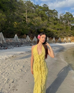 Outdoor shot of a bright yellow tiered ruffle halter maxi dress on a sunny beach