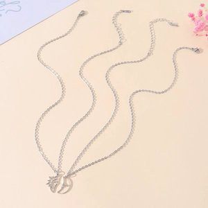 Minimalist stainless steel sun and moon pendant necklaces for couples on warm background