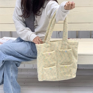 Detail of yellow fuzzy tote bag with four front pockets and decorative colorful buttons