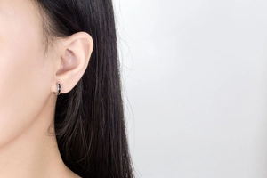 Close-up of minimalist silver hoop earrings with black enamel inlay on a female model