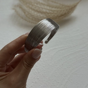 Close-up of silver multilayer open cuff bracelet featuring spherical end caps and wire texture