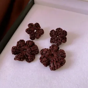 Handmade dark brown woven flower earrings with silver needles for a boho vacation look