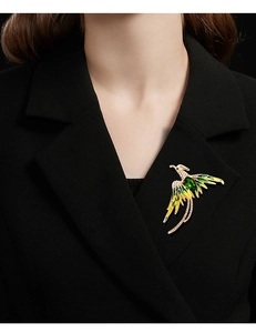 Detail of elegant gold phoenix brooch with green enamel and rhinestones on black blazer