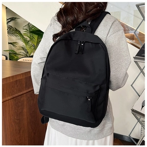 Rear view of model wearing a minimalist black nylon backpack with adjustable straps