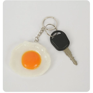 Vue détaillée du porte-clés œuf au plat réaliste avec anneau argenté et clé de voiture