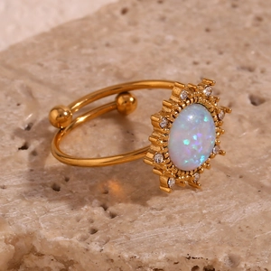 Macro view of 18K gold plated opal ring with sunburst zircon halo on a stone surface