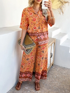 Détail d'un ensemble bohème avec chemise orange à fleurs et pantalon large fluide