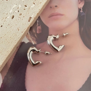 Detailed view of silver heart-shaped hoop earrings on elegant minimalist background
