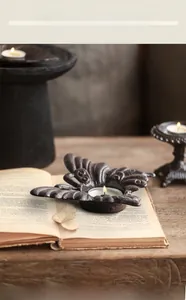 Détail d'un bougeoir papillon rétro en fonte avec une finition brune texturée rustique
