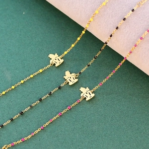 Close-up of golden crown bracelets with colorful yellow, black, and pink beads detail