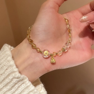 Detailed close-up of a beaded crystal bracelet with golden coin charm and bell pendant
